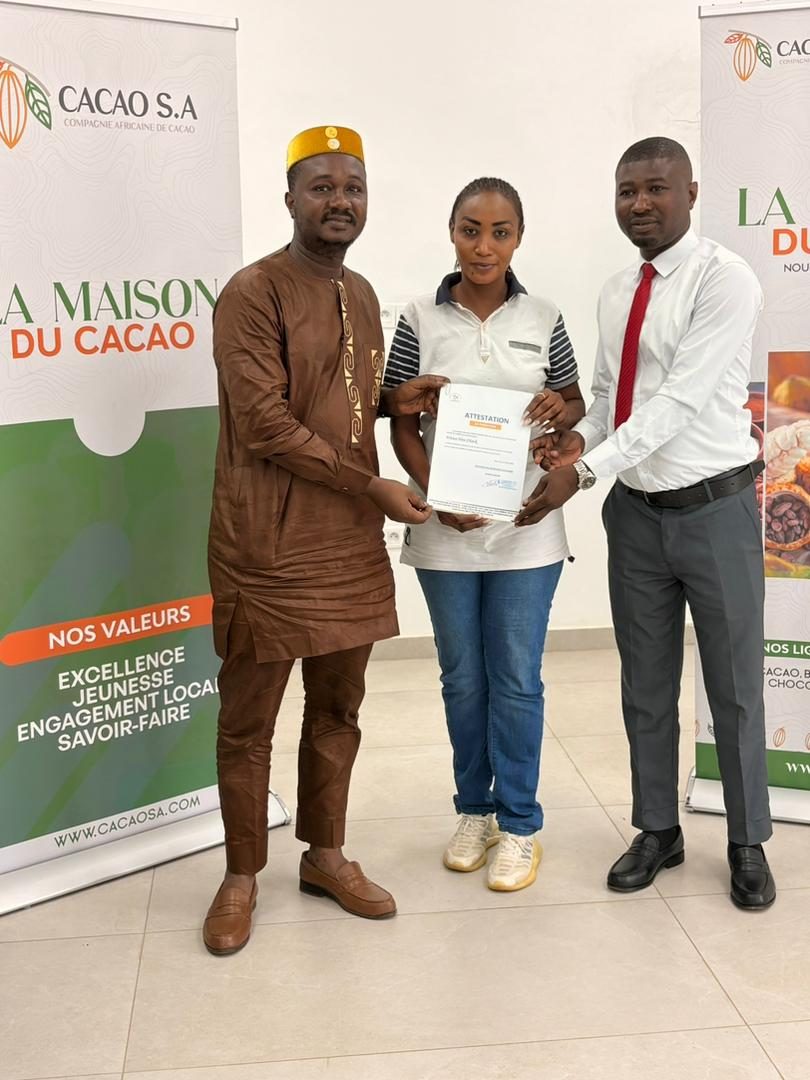 Remise d’une attestation devant l’oriflamme « La Maison du Cacao »