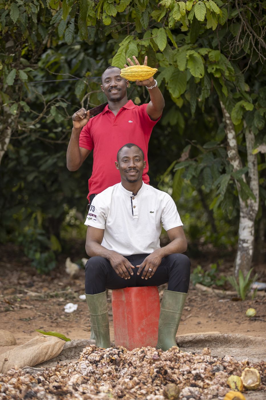 Deux producteurs de cacao dans une plantation, une cabosse à la main